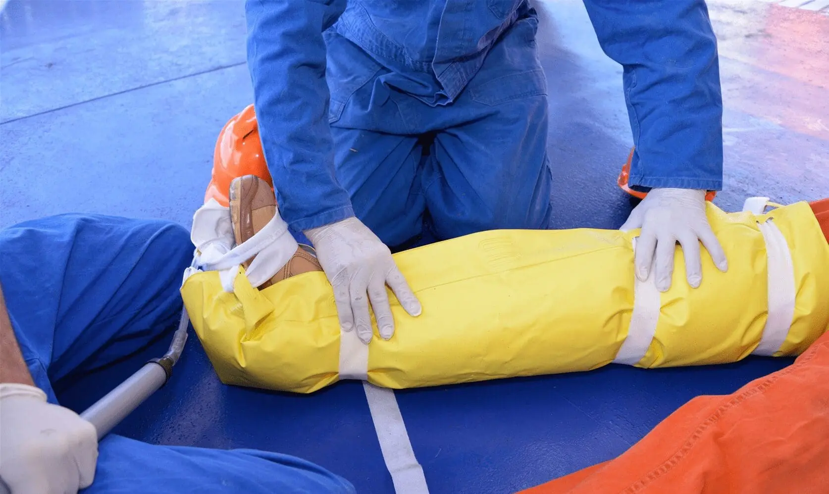 Maritime first aid instructor demonstrating recovery position technique on training dummy for STCW Basic First Aid course