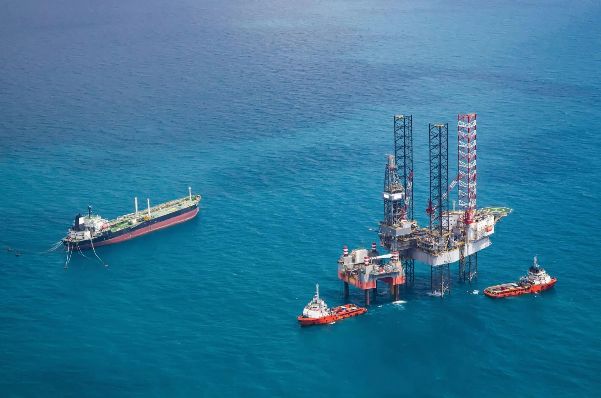 Offshore oil platform with support vessels and tanker ship in deep blue ocean waters during maritime operations