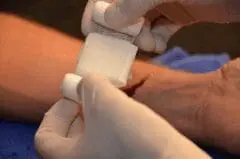 Hands demonstrating proper bandage wrapping technique for basic first aid training on maritime vessels
