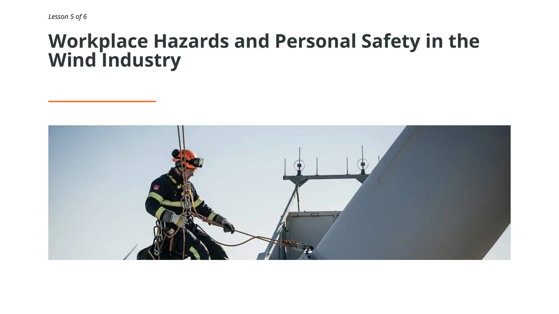 Wind turbine technician wearing safety harness and hard hat performing maintenance work on offshore wind turbine nacelle during Lesson 5 of wind energy safety training course