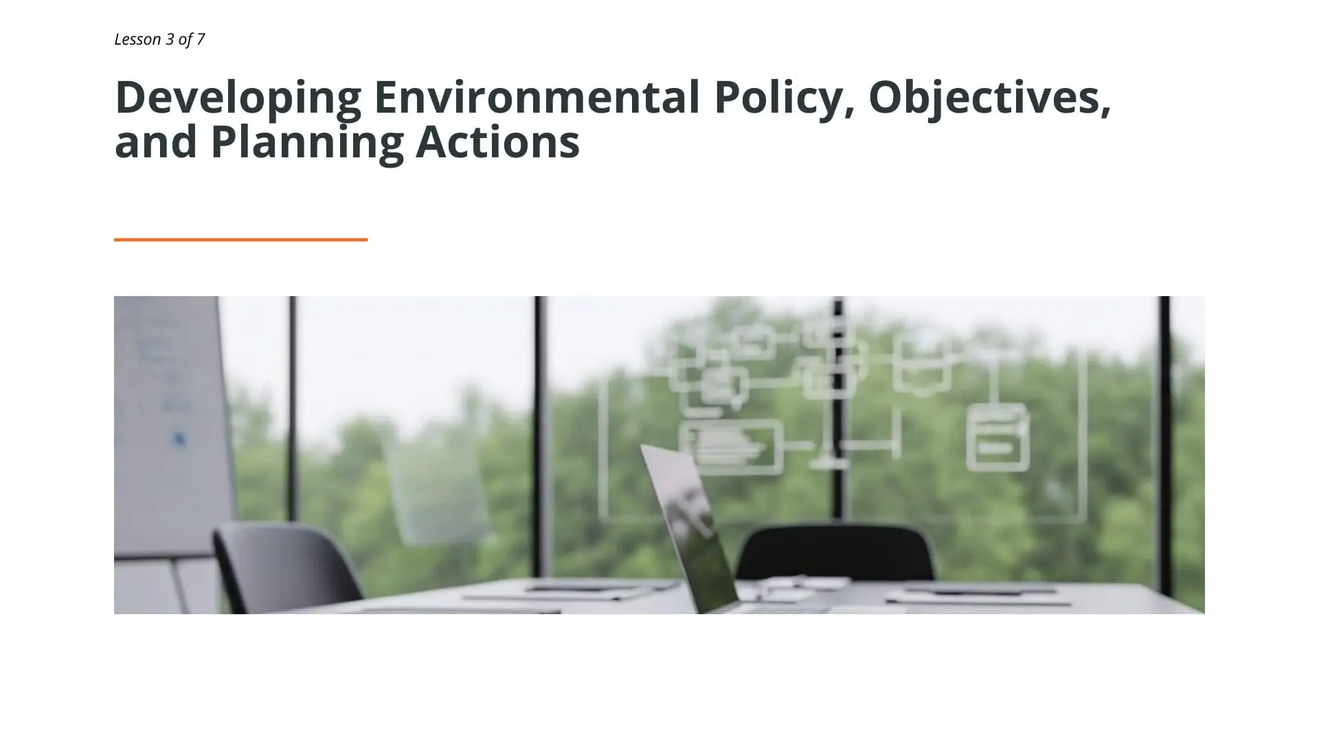 Modern office meeting room with green forest view through windows, laptop displaying planning diagrams, representing environmental policy development for ISO 14001 training