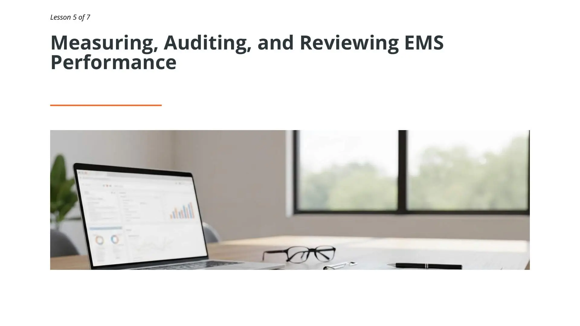 Laptop displaying EMS performance data analytics dashboard with charts and graphs on office desk for ISO 14001 environmental management systems training