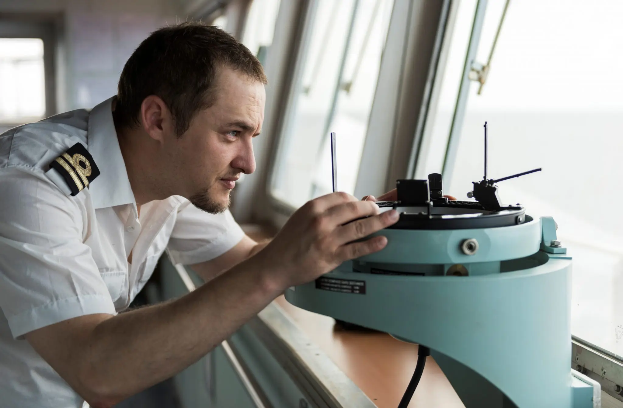 Maritime safety officer in uniform inspecting ship navigation equipment during onboard safety training for STCW certification