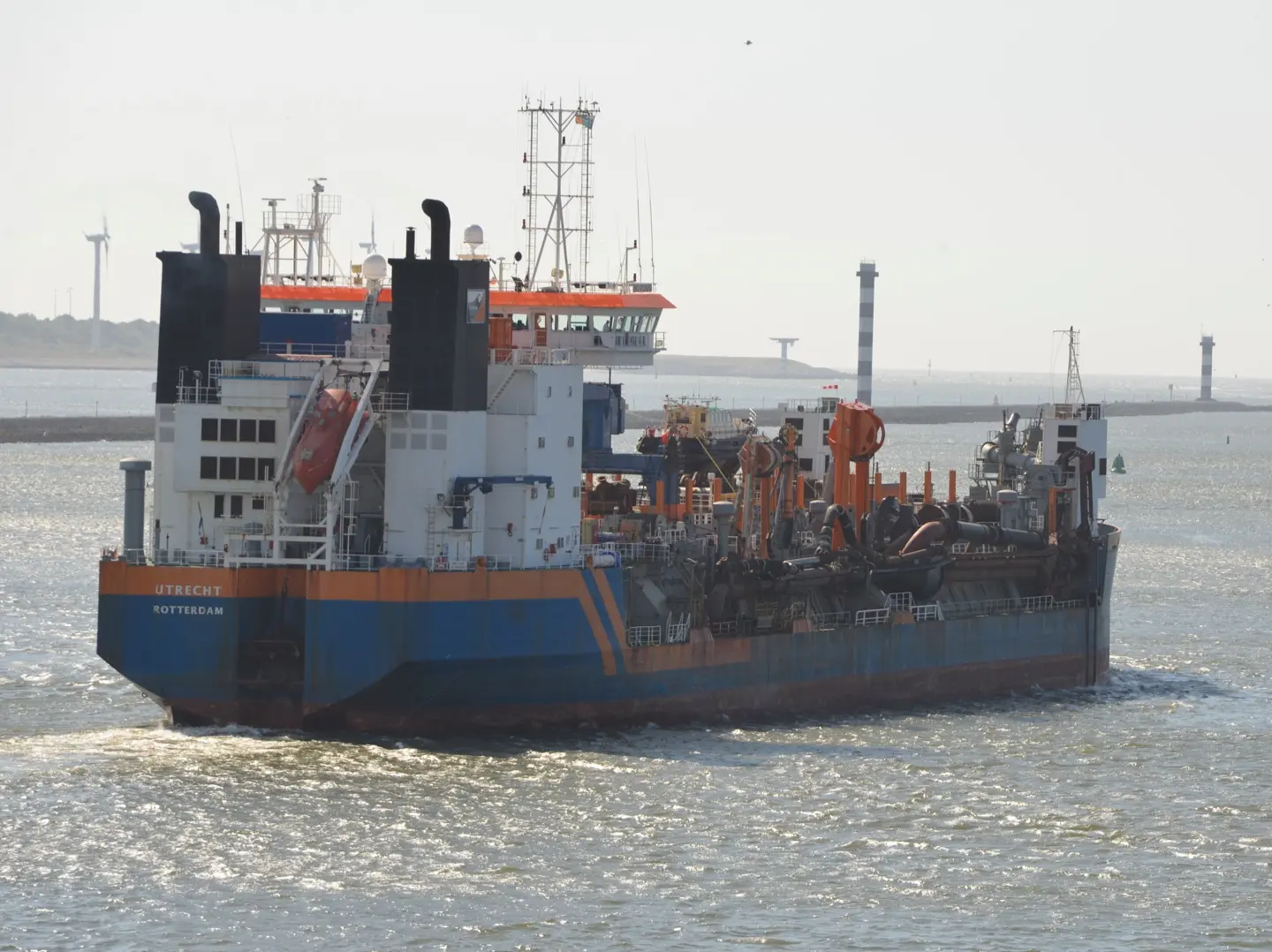Industrial multipurpose vessel with orange and blue hull, demonstrating maritime safety operations and ship officer responsibilities in coastal waters