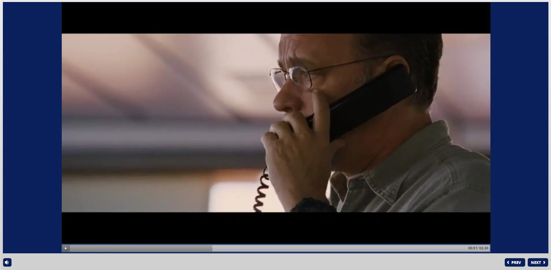Seafarer wearing glasses using rotary phone during STCW Security Awareness training with water backdrop